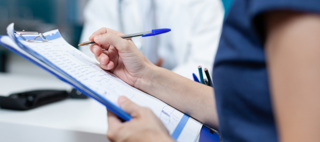 Close da mão paciente escrevendo informações médicas no documento