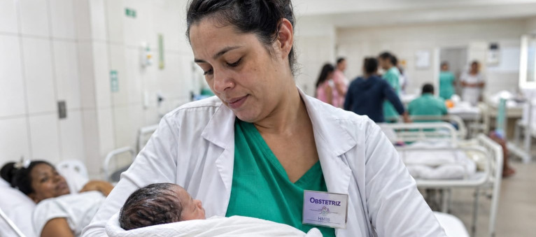 Obstetriz carregando um bebê no colo