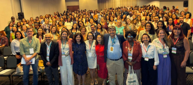 Muitas pessoas em um auditório, pousando para uma foto