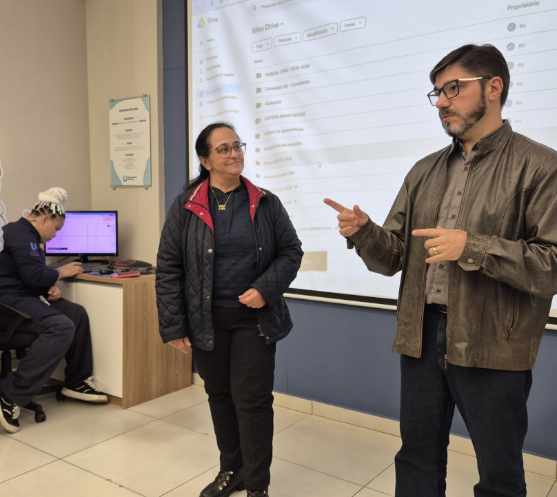 Pessoas conversando em pé com uma apresentação ao fundo