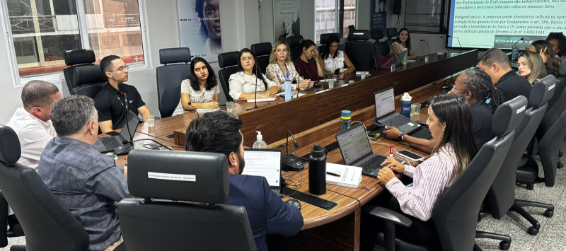 Pessoas sentadas em uma mesa de reunião no Coren-DF