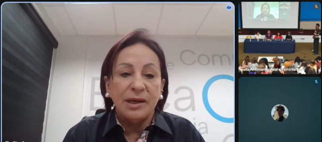 Pessoa falando por vídeo para outras pessoas que estão em um evento presencial