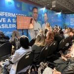 Uma mulher falando ao microfone para um público a sua frente